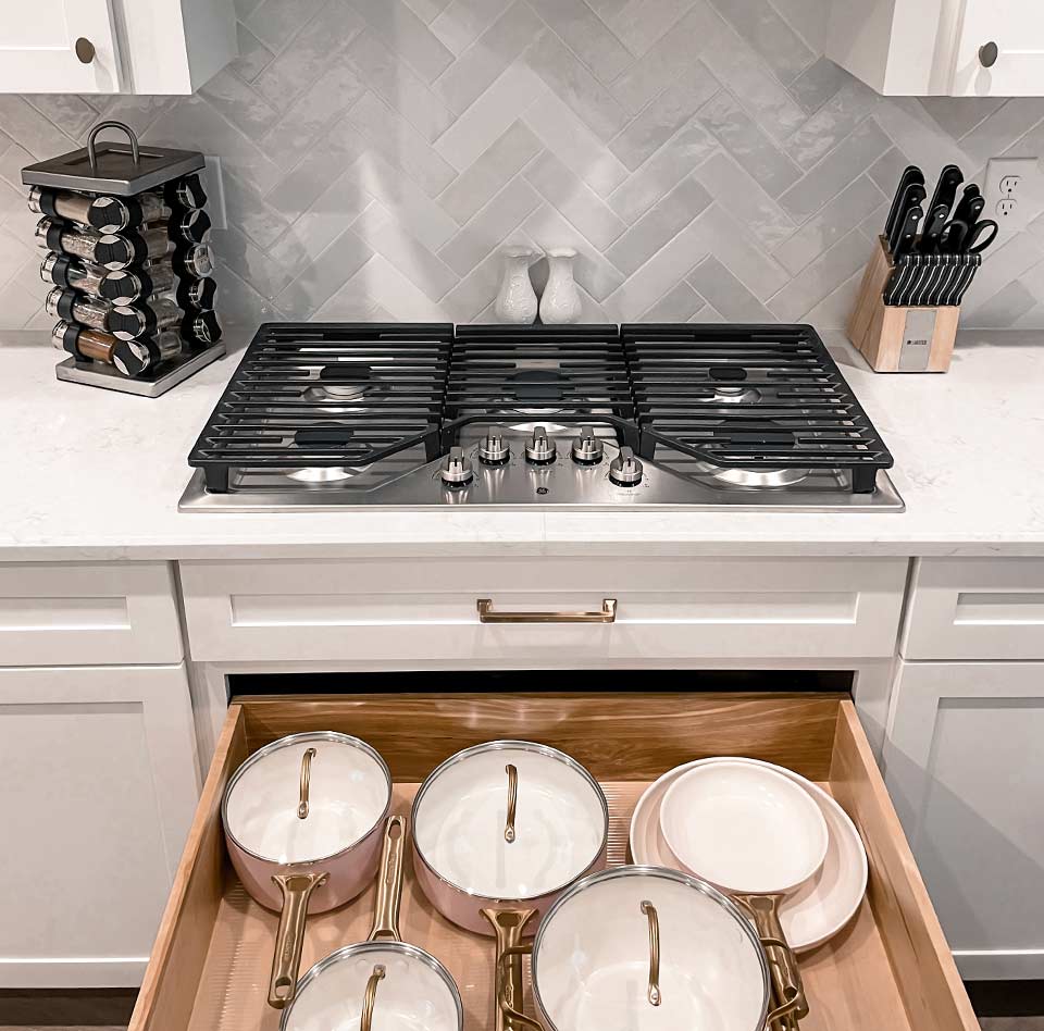 Beautifully organized kitchen with the stove drawer open underneath showing organized pots and pans